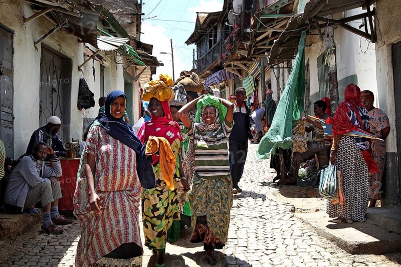 Women wearing traditional clothes stroll through a busy alley in Harar, Harar, Oromia, Ethiopia