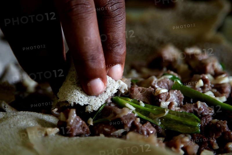 Hand grabs Injerra with tibs during an Easter meal, Lalibela, Amhara, Ethiopia