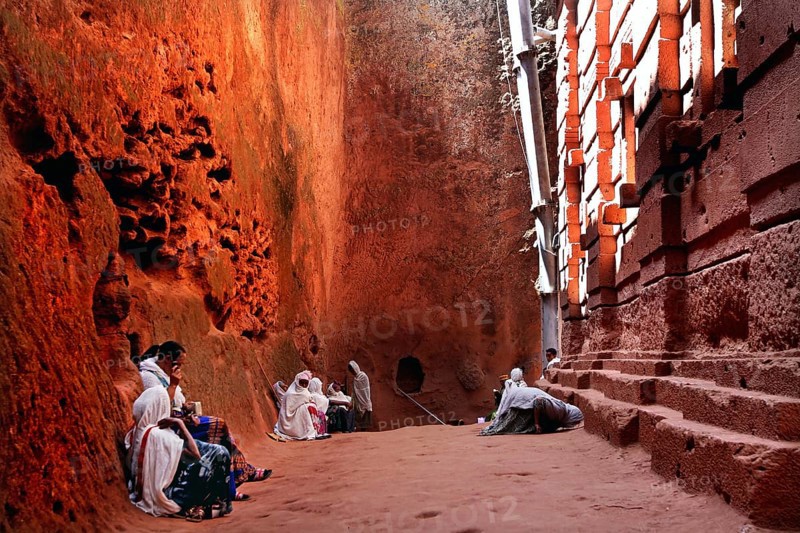 People wearing traditional clothing sit at Bete Emanuel, impressive rock architecture, Lalibela, Amhara, Ethiopia