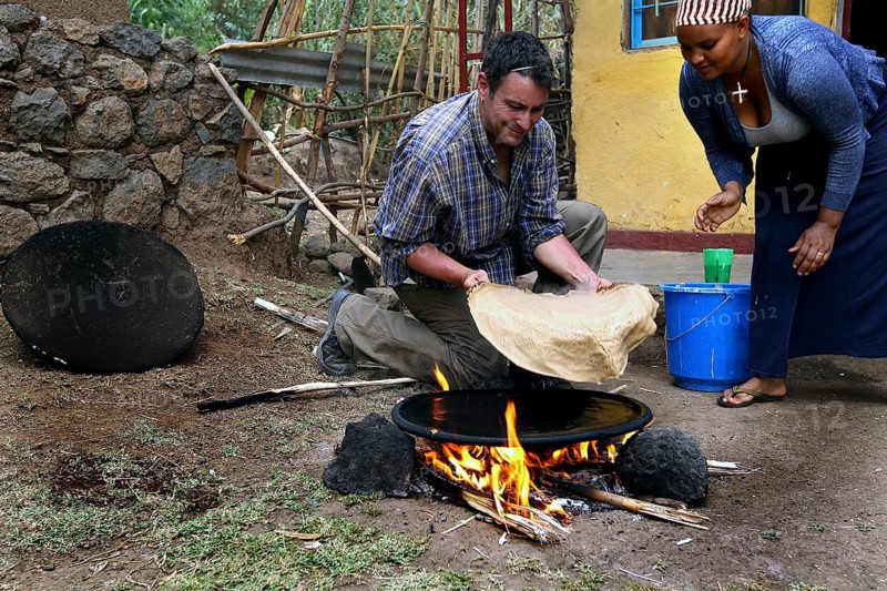 Roland and Worknesh prepare injera together on a fireplace, Lalibela, Ethiopia