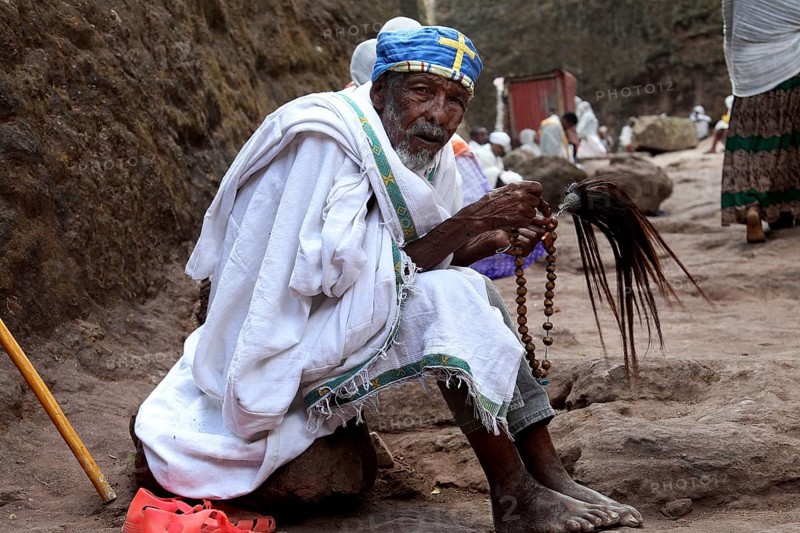 A praying monk in traditional clothing on a stone path, Lalibela, Amhara, Ethiopia