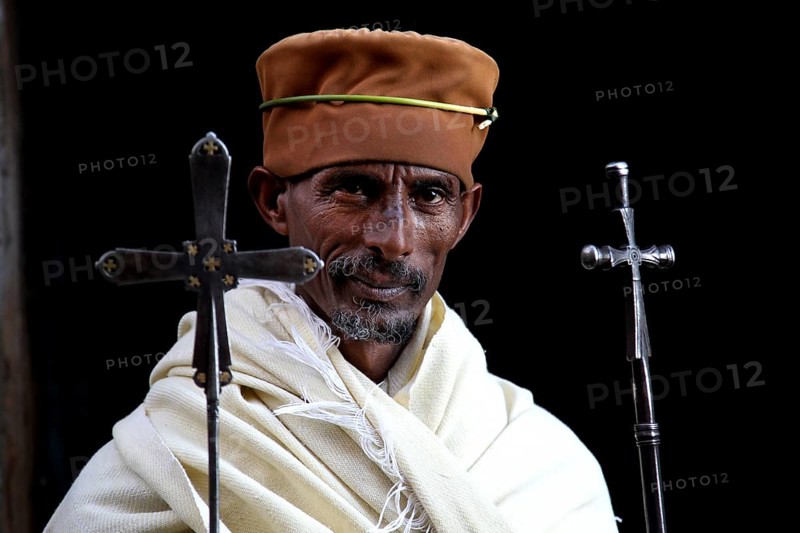 Priest with crosses and traditional clothing against black background, Lalibela, Lasta Mountains, Ethiopia