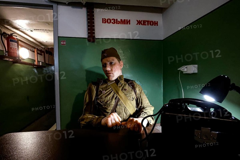 A person in military uniform sits in an atmospherically lit bunker in Plokstine, Plokštine, Telšiai County, Lithuania