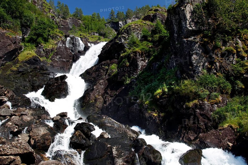 The impressive Låtefossen waterfall amidst rocky landscape and lush greenery, zero