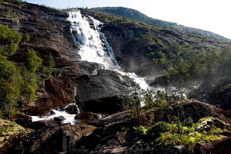 Majestic waterfall falls over rocks amidst green vegetation, Langfossen, Norway