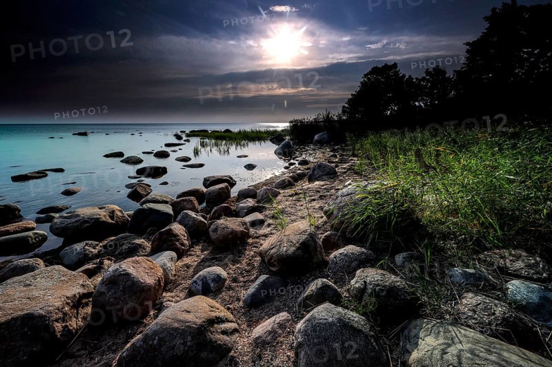 Rocky coast during sunrise with calm water and overcast sky in Altja, Altja, Estonia