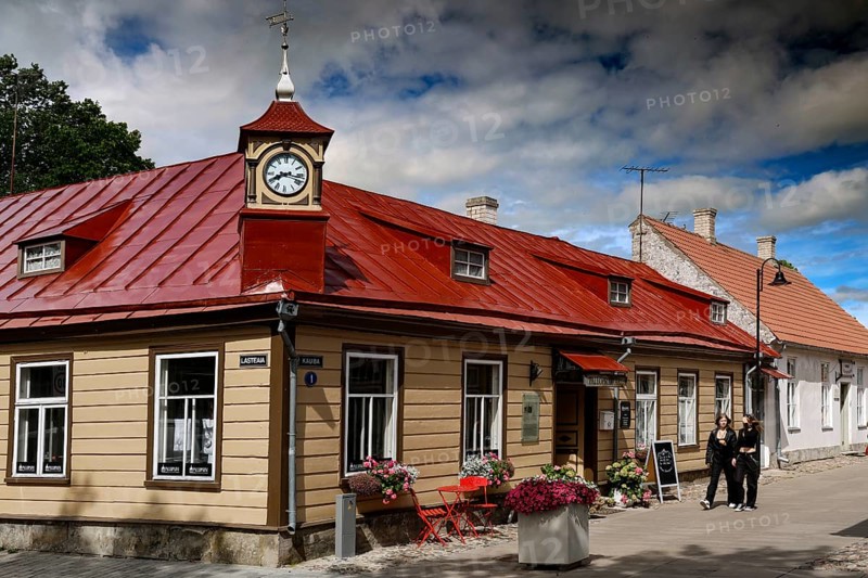 Historic building with red roof in the old town, people walking along the street, Kuressaare, Saaremaa, Estonia
