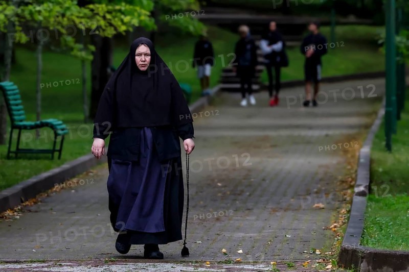 Nun with walking stick walks through the park in Kuremäe, Kuremäe, Pühtitsa, Estonia