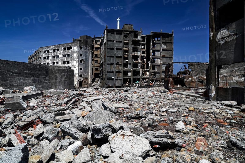 Abandoned ruins of Gunkanjima with crumbling buildings and debris under clear skies, Nagasaki, Japan