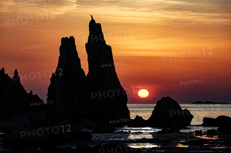 Sublime rock formations at sunrise silhouetting against the orange sky, Kushimoto, Japan