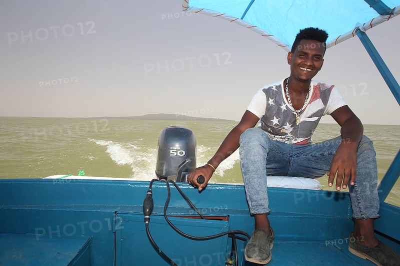 Captain rides a motor boat on Lake Tana under a blue sky, Lake Tana, Ethiopia