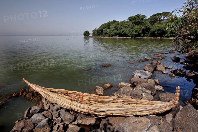 Papyrus boat is lying on a rocky shore with a view of Lake Tana, zero