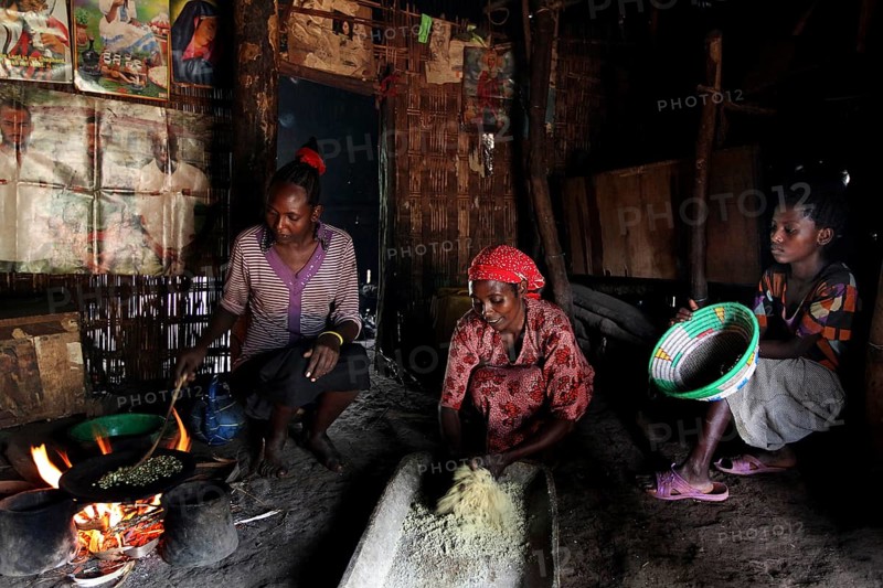 Women in a hut preparing food traditionally with mortar and pestle, Yirga Alem, Ethiopia