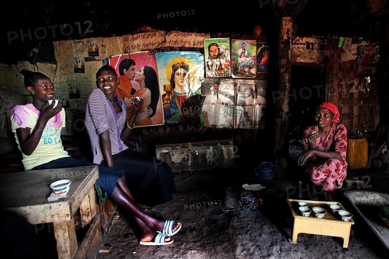 Women sitting in a cozy hut laughing and enjoying time together, Yirga Alem, Ethiopia