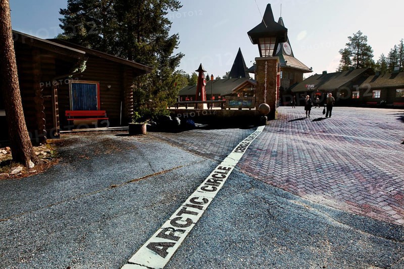 Arctic circle marking on cobblestones in front of picturesque buildings, Napapiiri, Finland