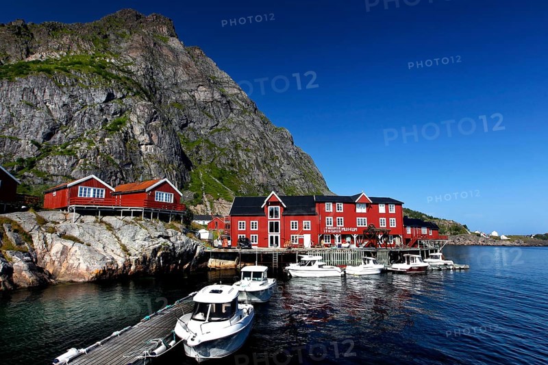 Red houses and boats in the harbor of Å in front of impressive rock, Å, Moskenesøy, Norway
