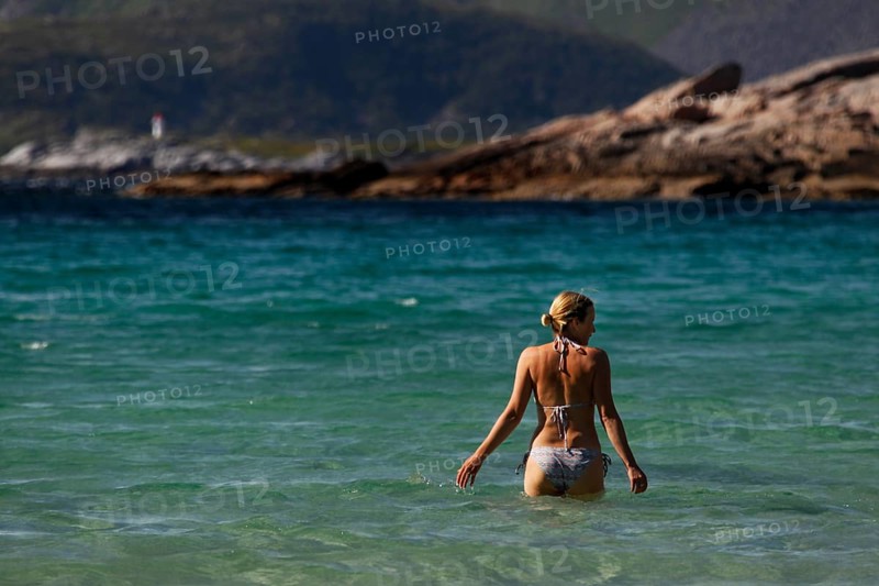 Woman bathing in clear blue water on Rårvik beach in Lofoten, Austvågøy, Lofoten, Norway