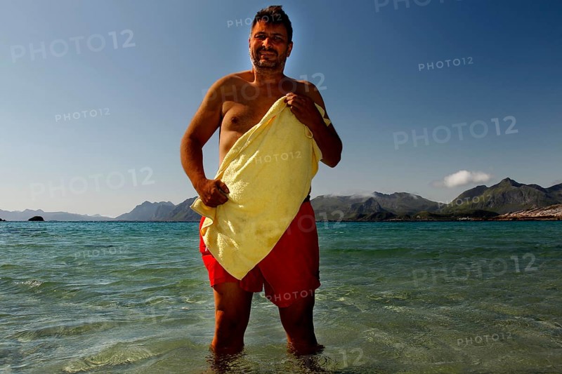 Summer day on Austvågøy beach with a man in the warm, clear water of Lofoten, Lofoten, Nordland, Norway