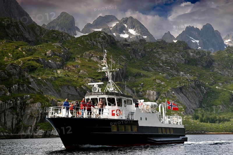 Tourists enjoy a boat trip in Trollfjord with mountain backdrop, Austvågøy, Raftsund, Norway