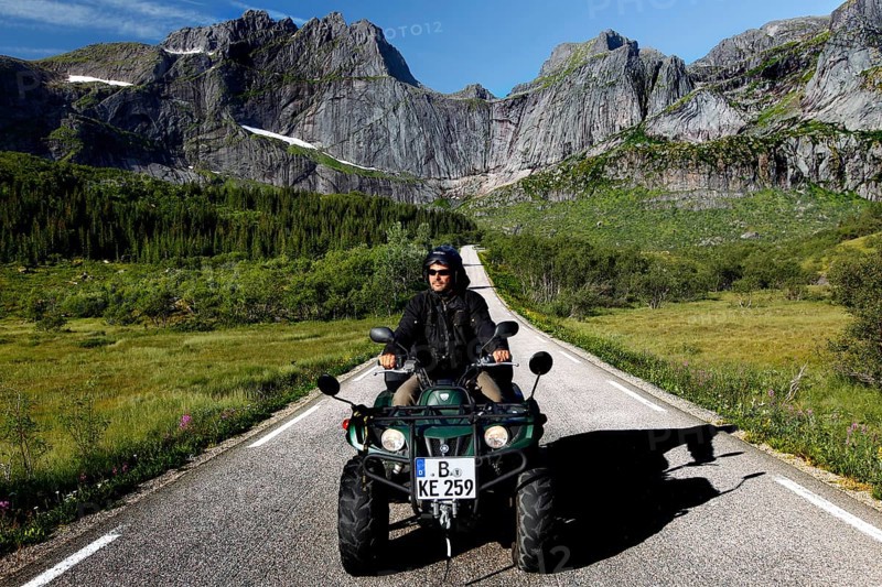 Person riding on ATV on a picturesque road in Flakstadøy, Flakstadøy, Lofoten, Norway
