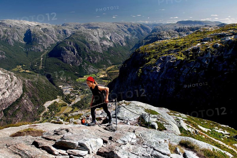 Hikers climbing Mount Kjerag with breathtaking mountain scenery in the background, Lysefjord, Norway