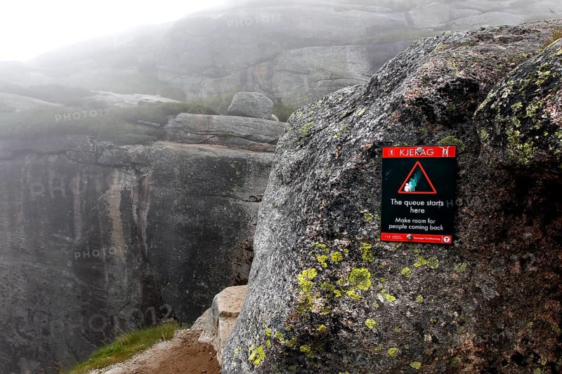 Warning on rock against the backdrop of the misty Kjerag landscape, Lysefjord, Rogaland, Norway
