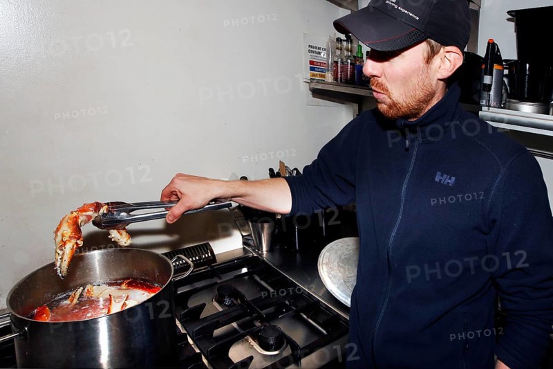 Man cooks king crab in a large cooking pot in the kitchen, Sarnes, Norway