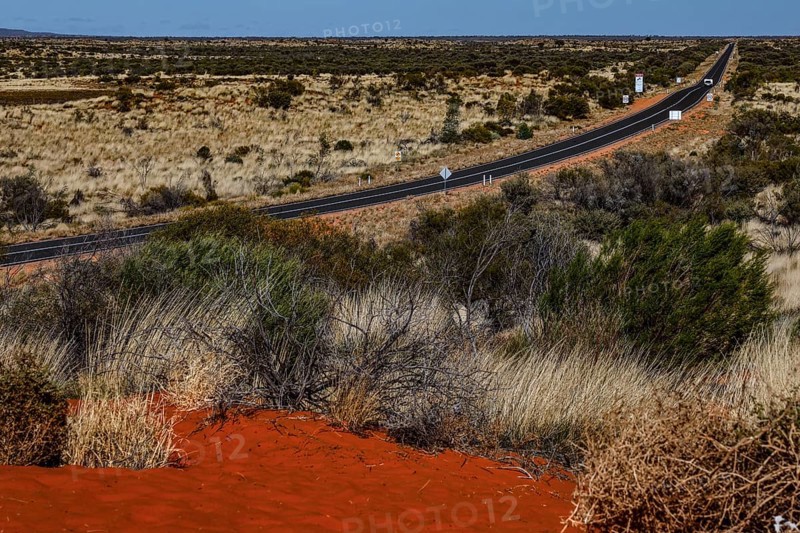 Long desert road through the Australian outback with red sand and vegetation, zero