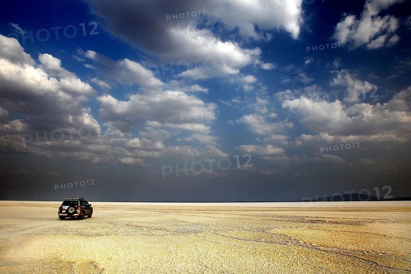Land cruiser under cloudy sky in wide desert landscape, Dallol, Asale, Ethiopia
