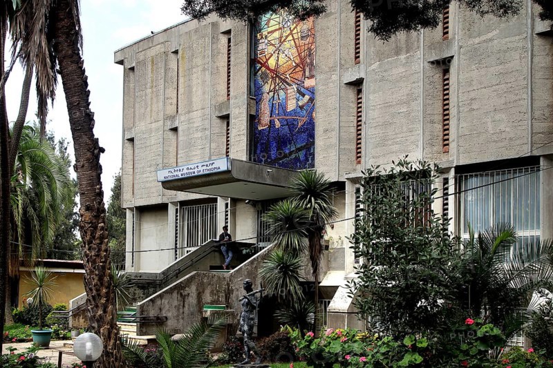 Impressive concrete building with wall art surrounded by lush vegetation, Addis Ababa, Ethiopia