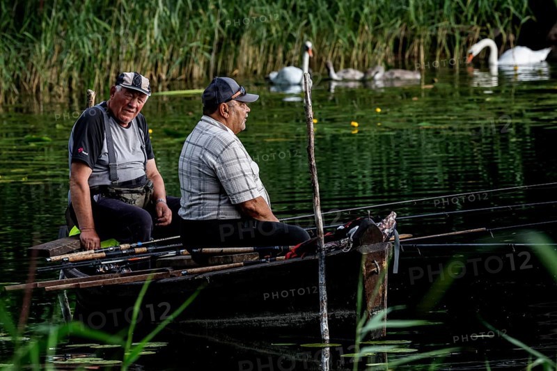 Two anglers sit in a rowboat on Lake Ilgis, surrounded by reeds and nature, Ignalina, Lithuania