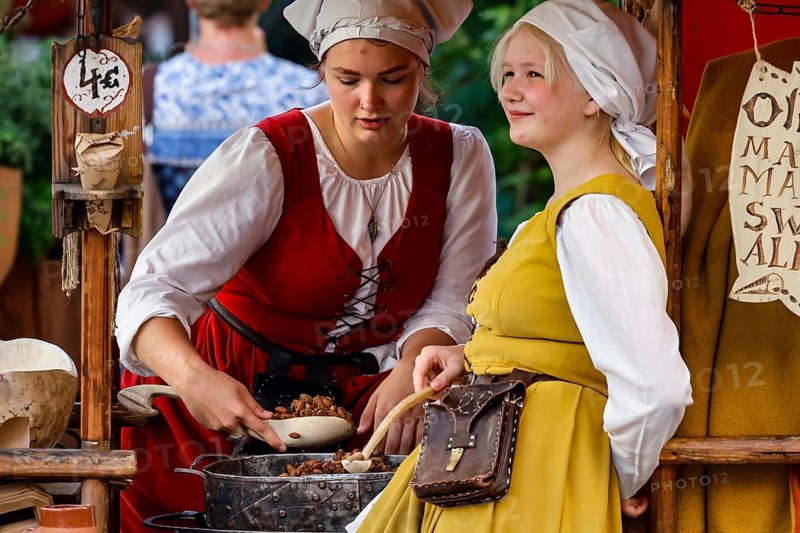 Saleswomen in traditional costumes serve customers at a medieval market, Tallinn, Harju, Estonia