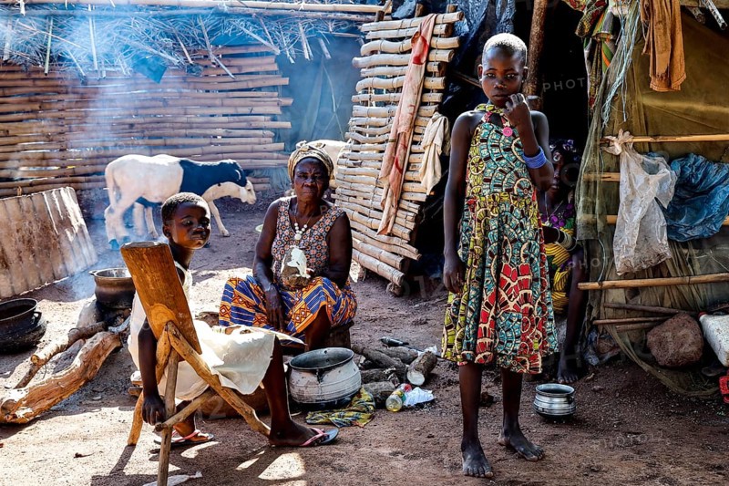 Women and children in the village, a woman preparing a meal surrounded by smoke and traditional ambiance, Brobo, Côte d'Ivoire