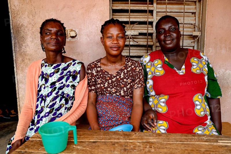 Three woman sitting together at a table smiling and enjoying company, Bouké, region, Côte d'Ivoire