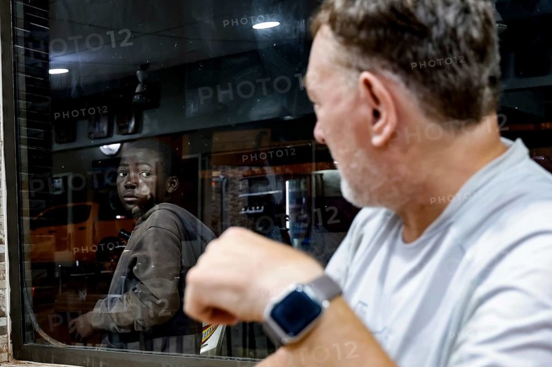 Two men in a Lebanese restaurant, one looking at the other through the window, Korhogo, CI, West Africa