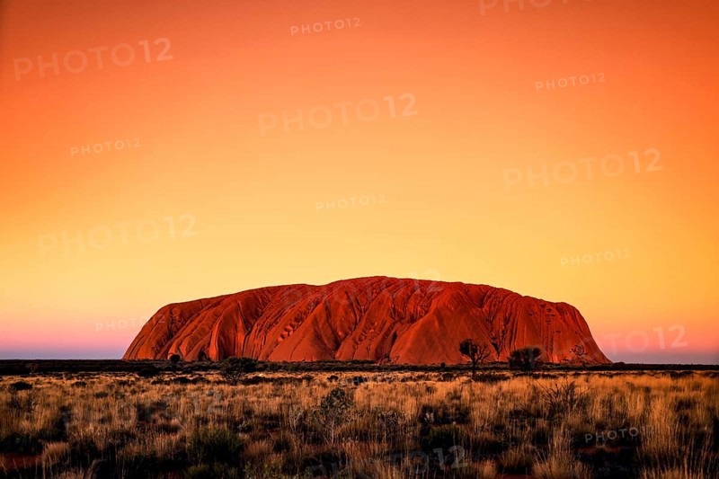 Uluru at sunset in the orange sky of the Australian outback, Uluru, Northern Territory, Australia