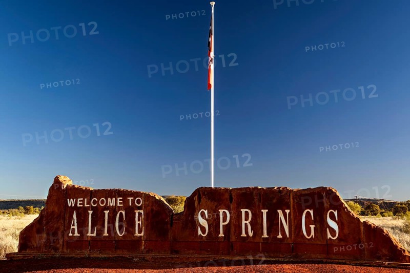 Alice Springs welcome sign with a flag against a clear sky, Alice Springs, Northern Territory, Australia