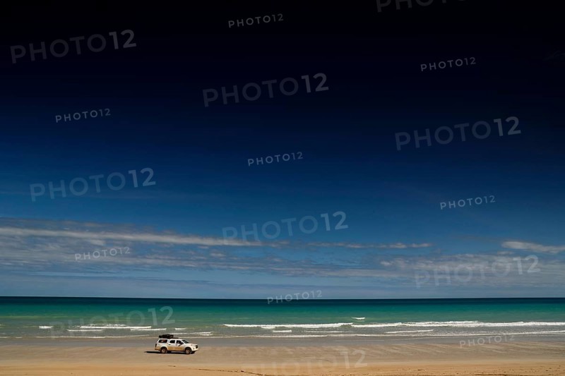 Vehicle on quiet shore of Cable Beach with clear, wide skies, Broome, Western Australia, Australia
