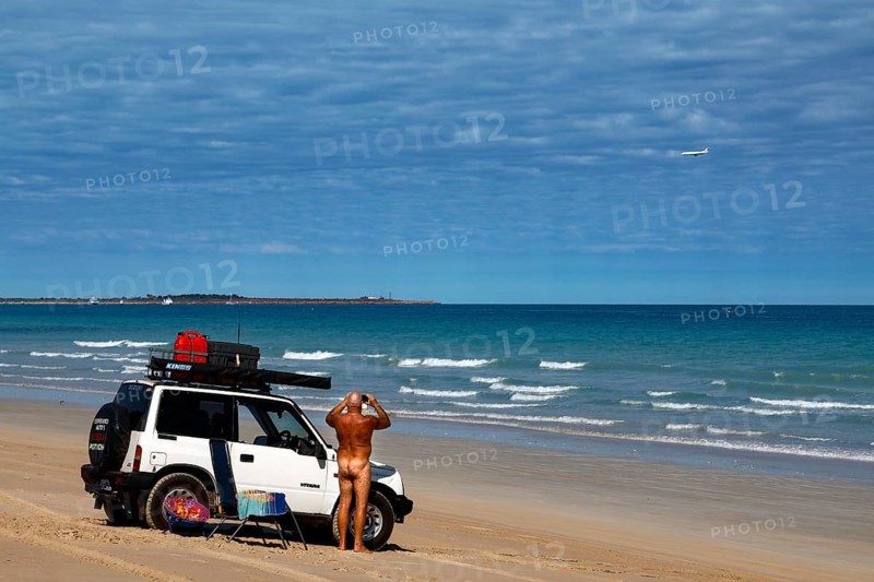 Jeep parked on a wide sandy beach with ocean views in sunny weather, Broome, Western Australia, Australia