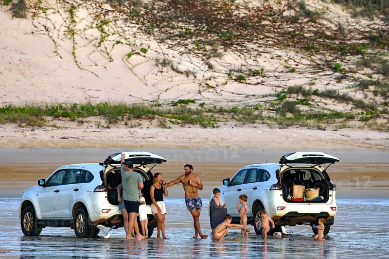 Beach visitors stand next to cars on the sandy beach of Cable Beach, Broome, Broome, Western Australia, Australia
