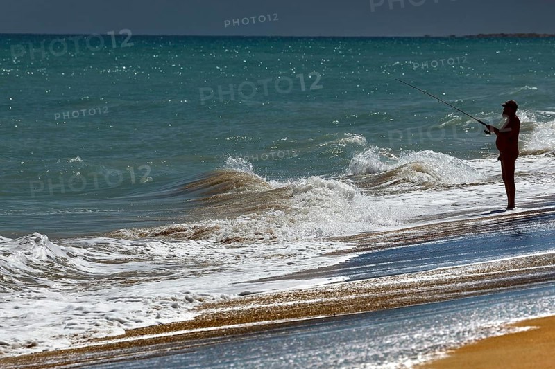 Angler standing on the beach fishing in the waves of Cable Beach, Broome, Broome, Western Australia, Australia