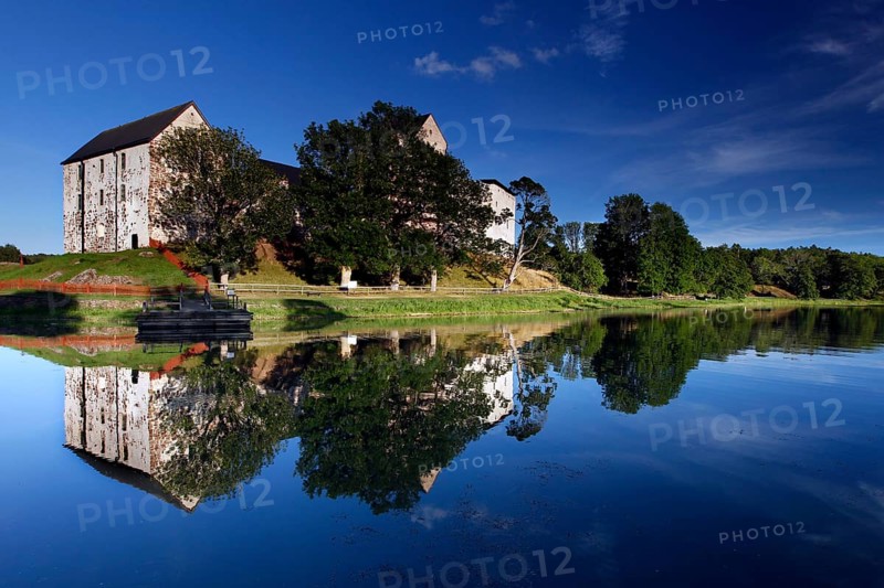 Kastelholm Castle in Åland with reflection in a quiet lake and wooded shoreline landscape, zero