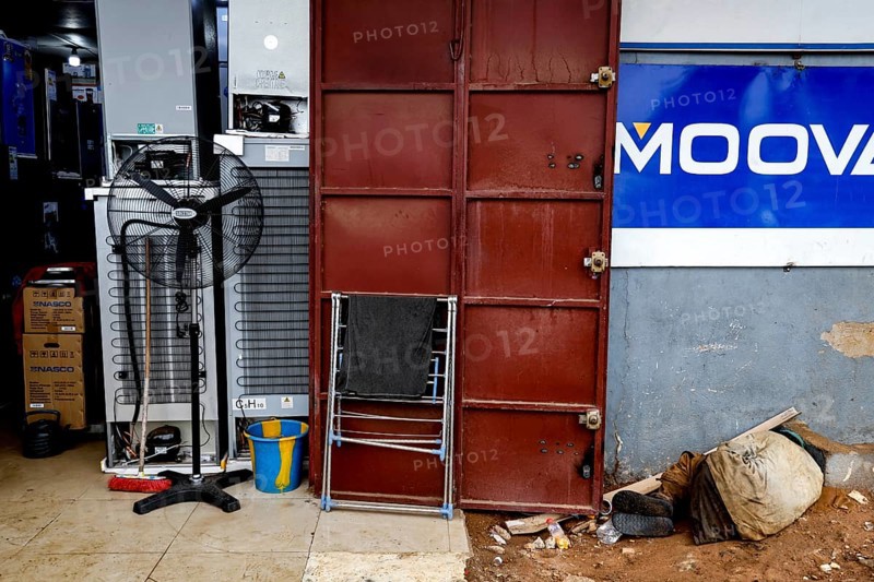 A locked door in an urban environment surrounded by dirt and scattered objects, Bouaké, Côte d'Ivoire