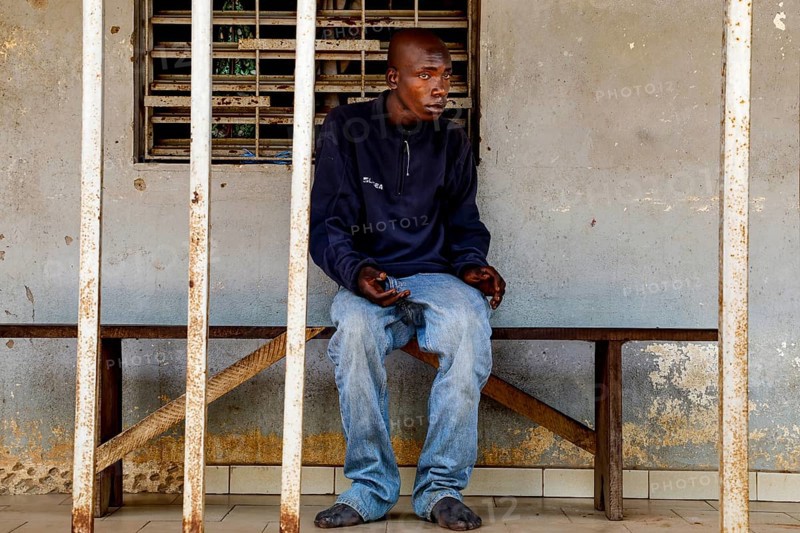 A man sits thoughtfully on a bench in a psychiatric facility in Bouaké, Bouaké, Saint Camille, Nimbo, Côte d'Ivoire