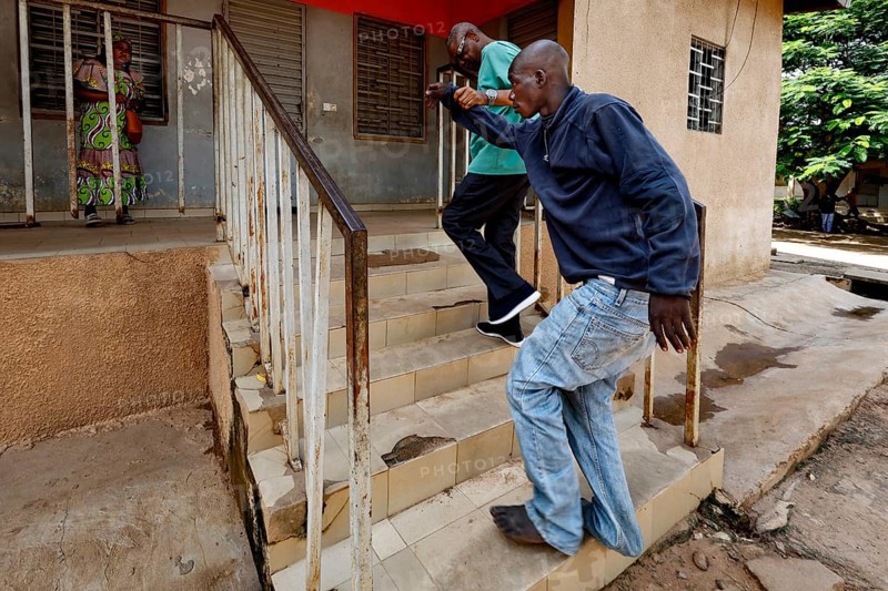 Nurse Albert helps a patient climb stairs, Bouaké, Nimbo, Côte d'Ivoire