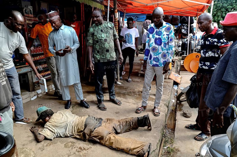 Homeless person receives care on the street, surrounded by helping people, CI Bouaké, Ivory Coast