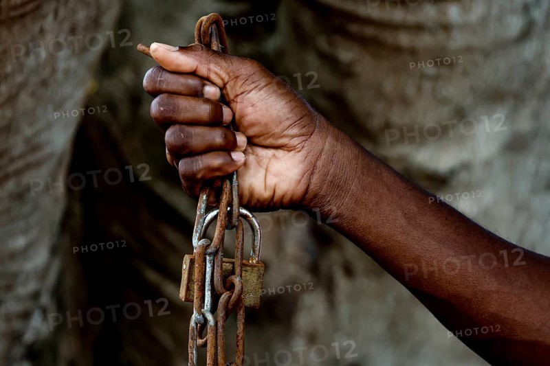A hand firmly holds a heavy chain as a symbol of suffering, Bouaké, Ivory Coast