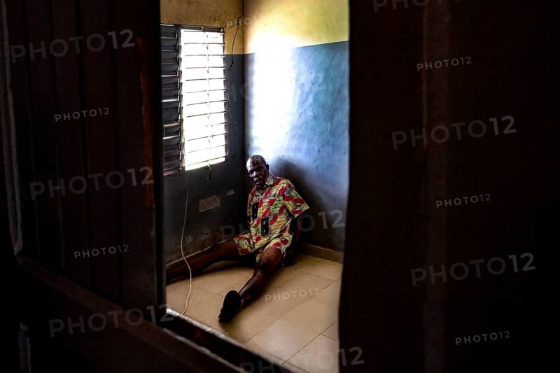 A man sits alone in a room at Saint Camille men's psychiatry, Bouaké, Côte d'Ivoire
