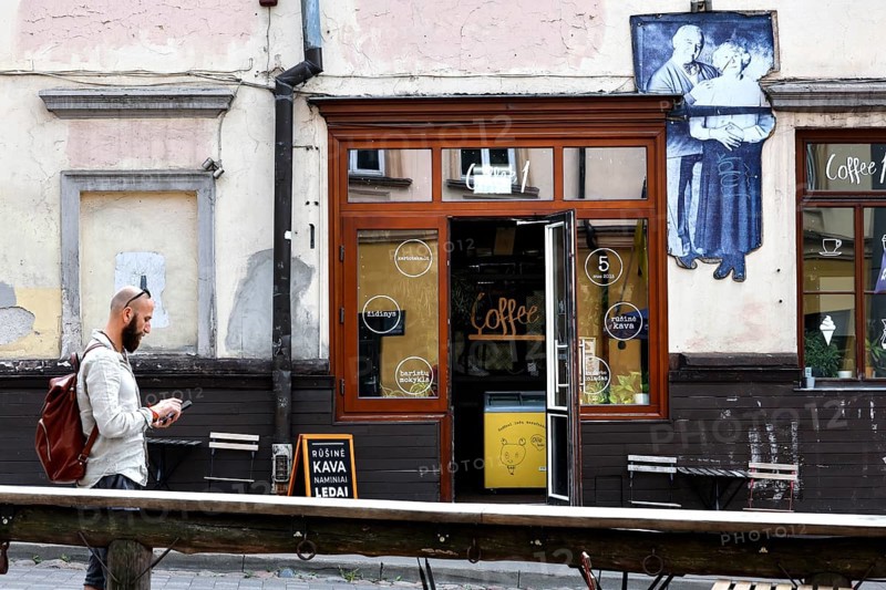 Passerby walks past a cafe in Uzupis, Vilnius, mural in the background, Vilnius, Vilnius County, Lithuania