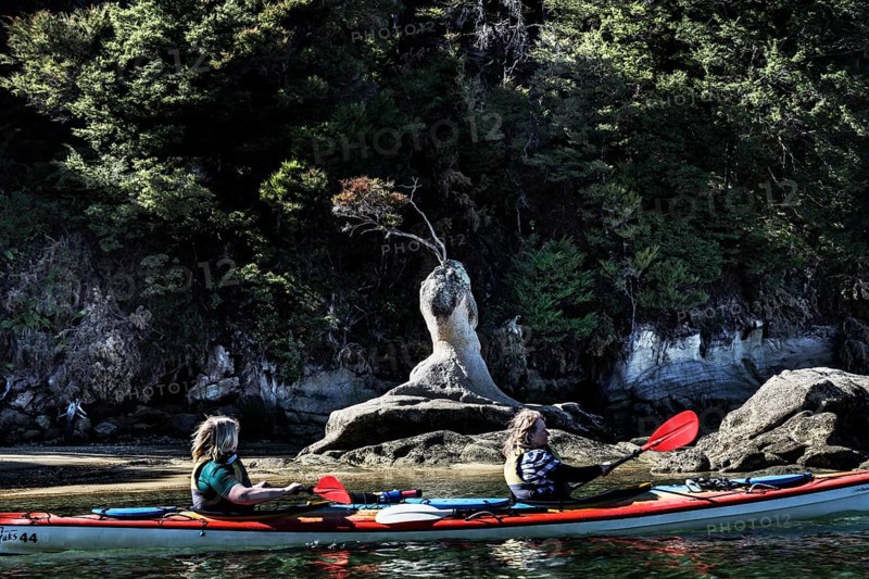 Two people kayaking in front of a rock formation on the water, Appletree Bay, Abel Tasman National Park, New Zealand